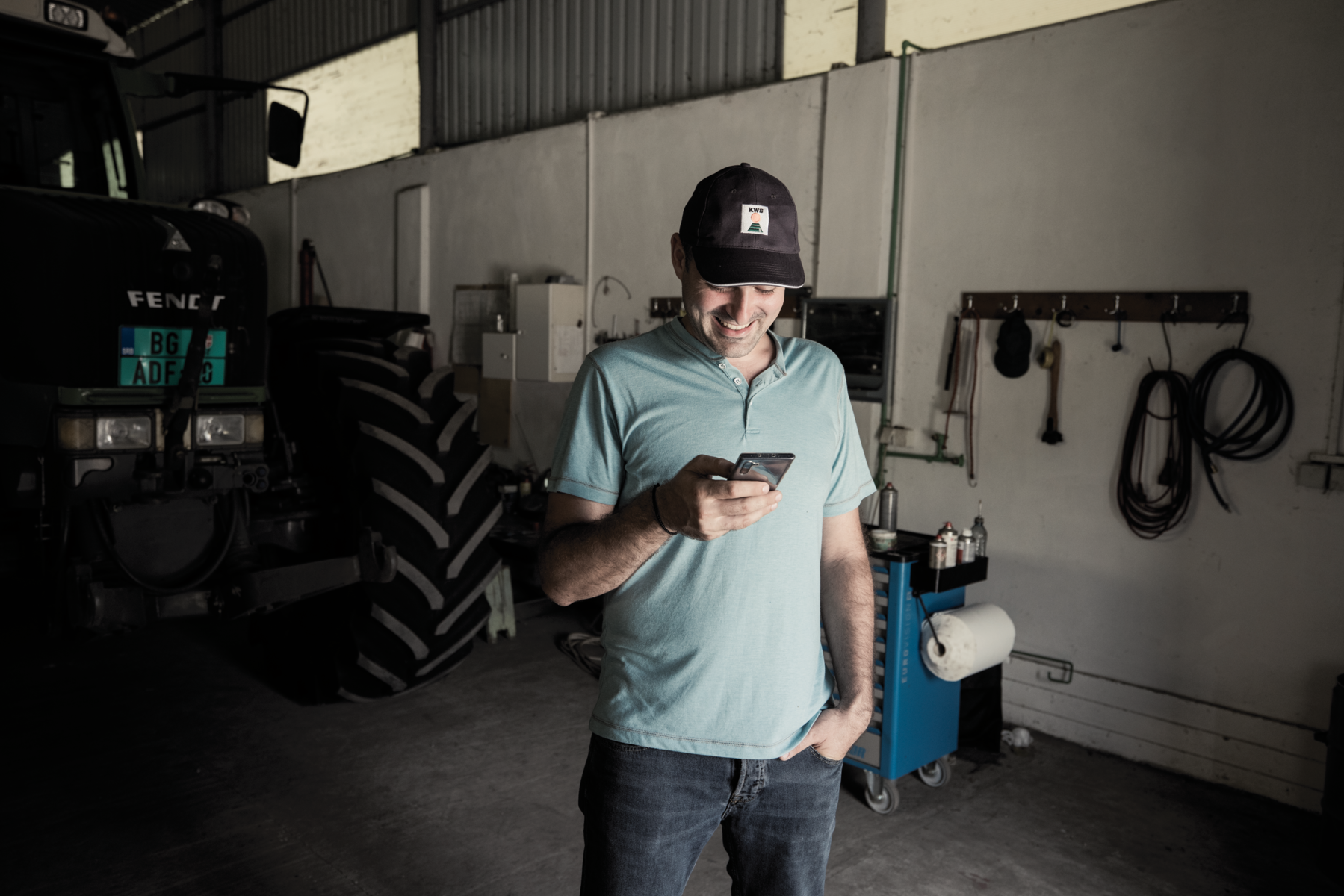 landmand ved traktor garage og smartphone