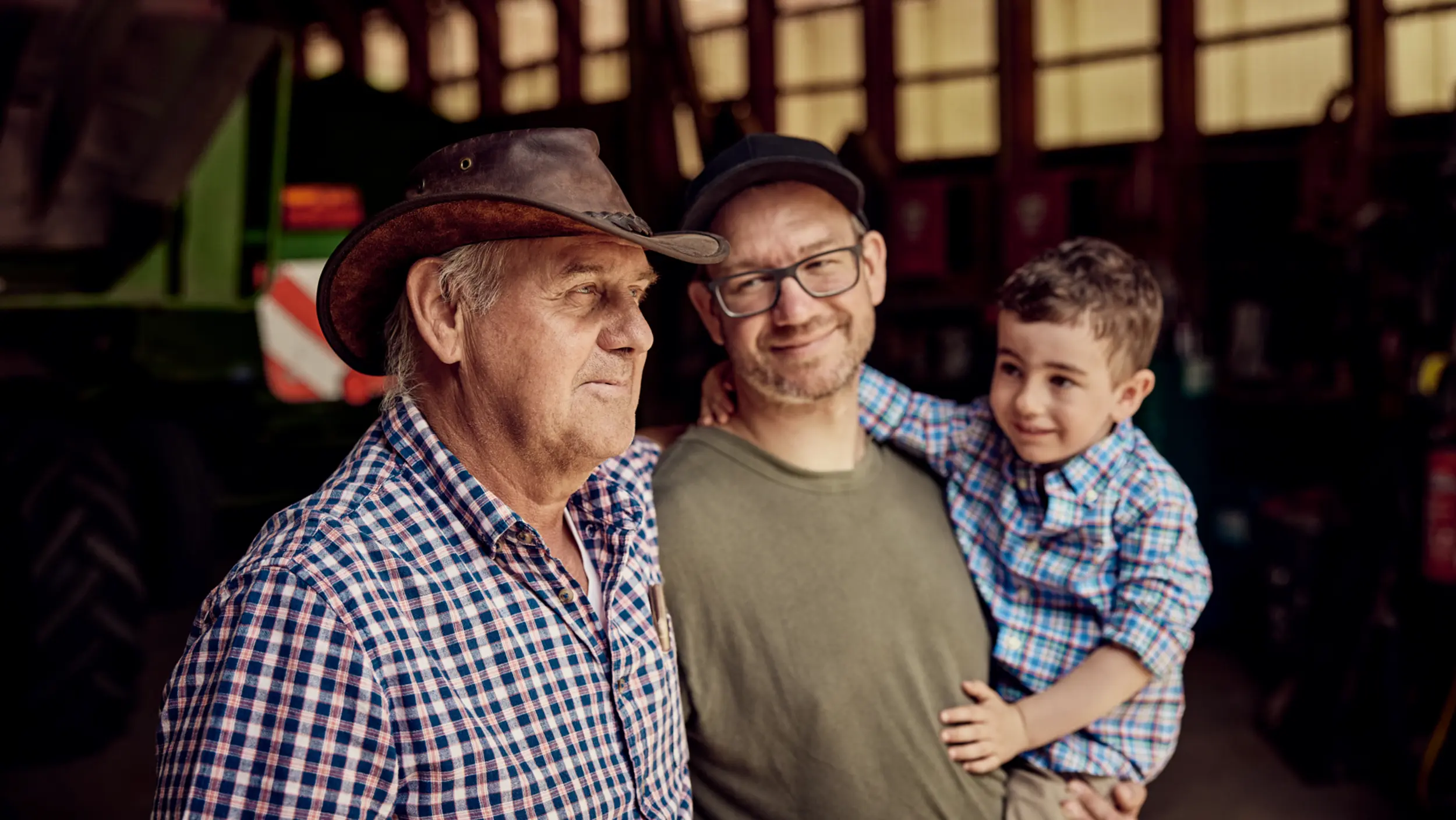 Großvater, Vater und Sohn stehen auf ihrem Bauernhof