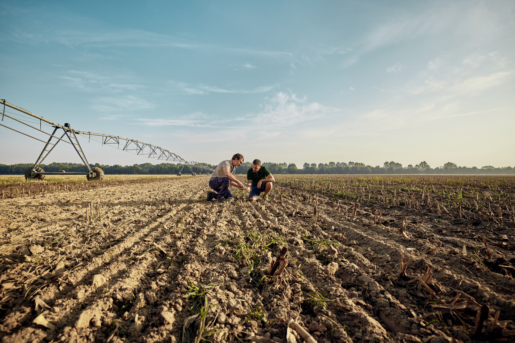 Ein Landwirt prüft mit einem KWS Mitarbeiter den Boden auf einem Feld