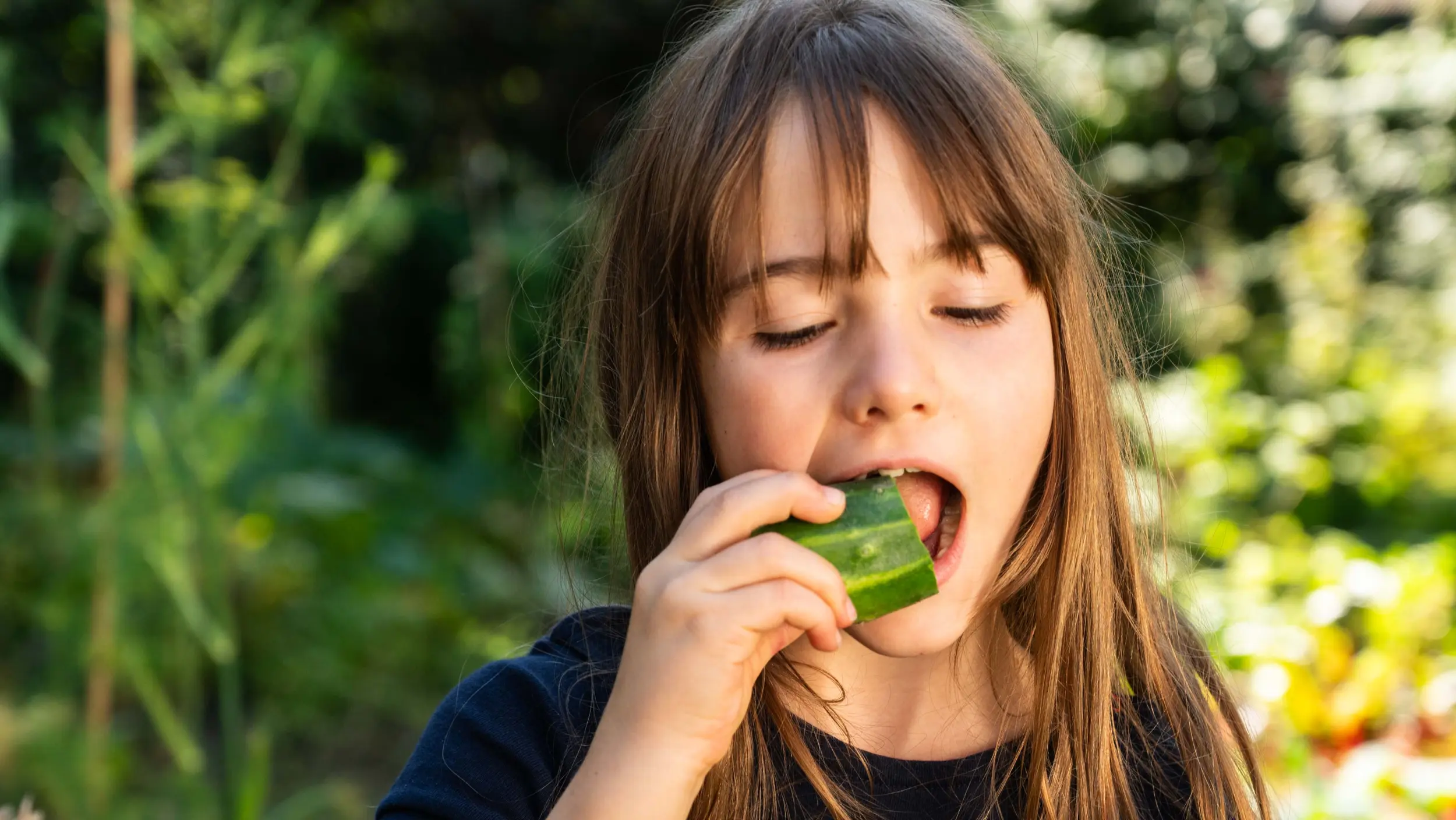 female student biting into a cucumber