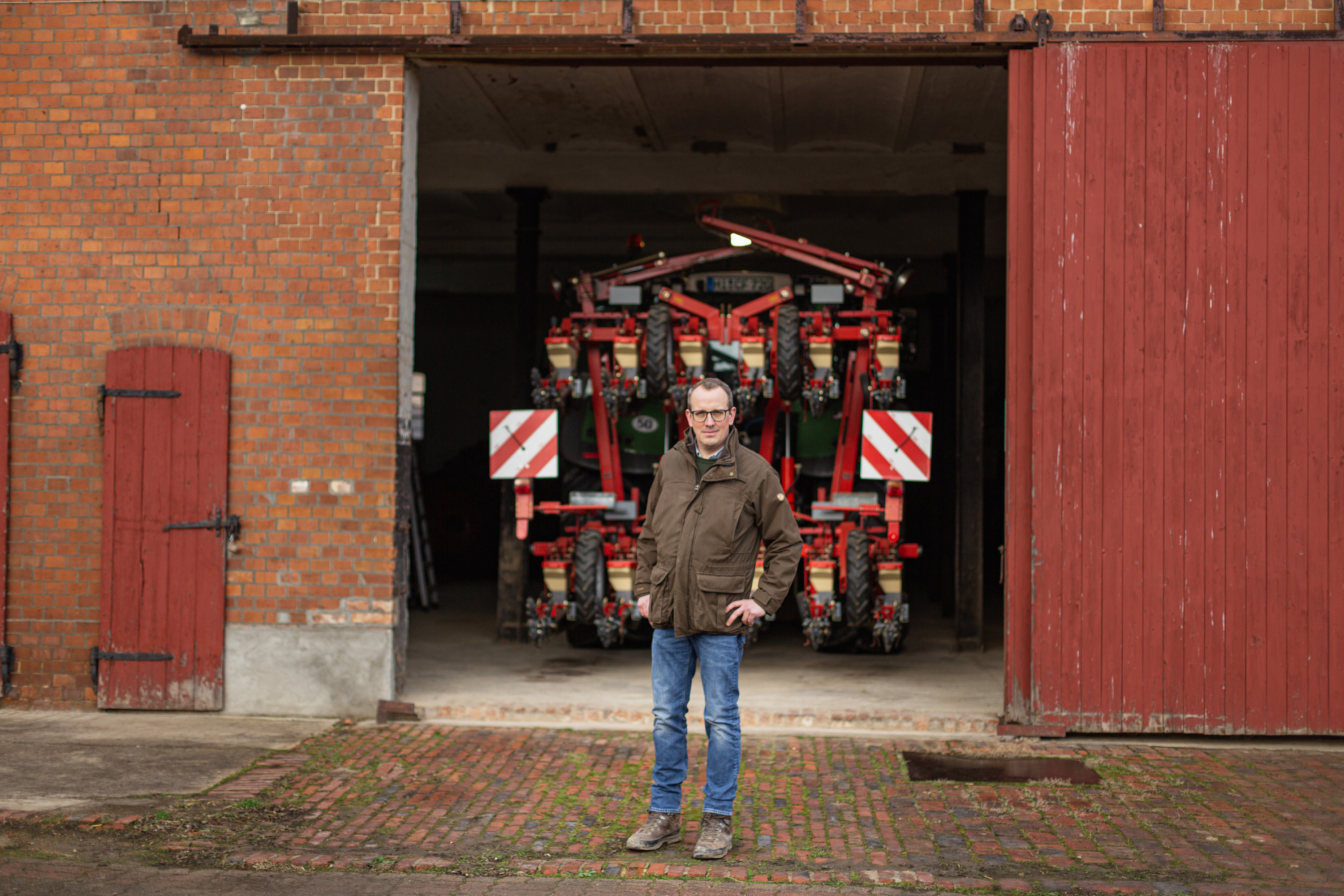 Farmer Christian Flögel is standing in front of a tractor with a seed drill on his farm in Dinklar.