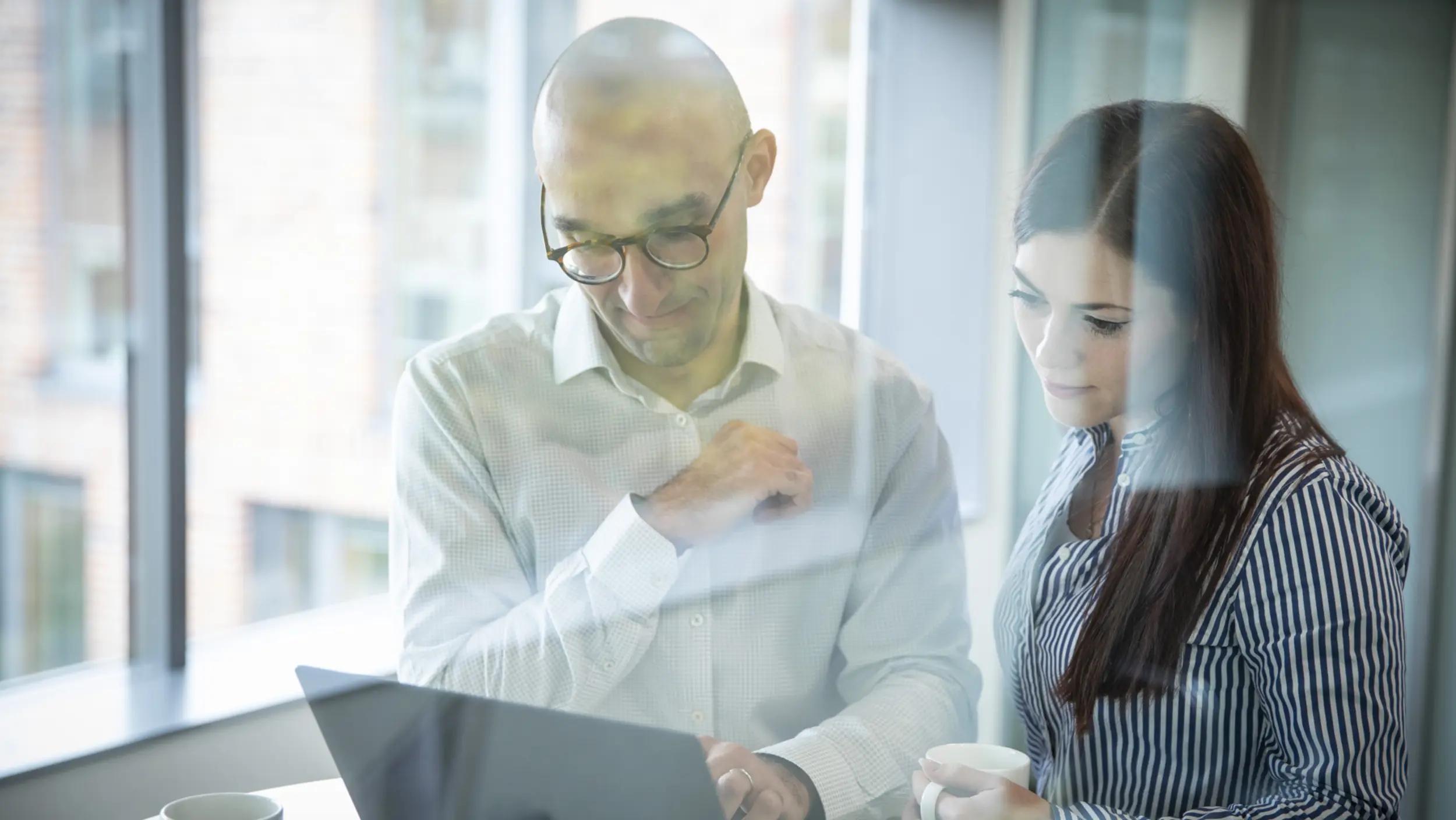 A man and a woman standing together in front of a laptop