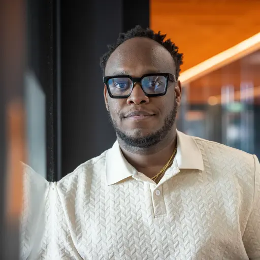 A male person leaning against the wall and looking into the camera