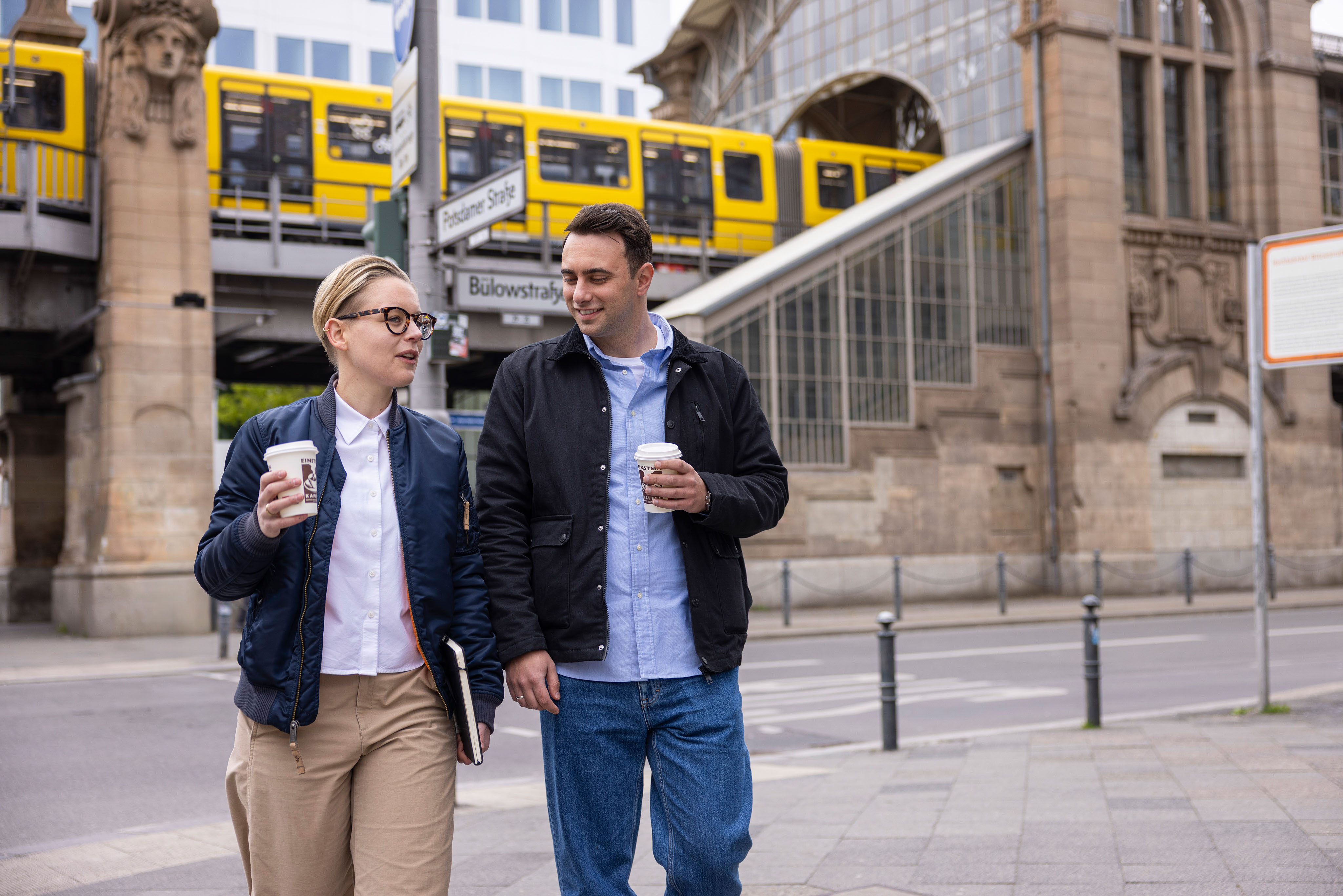 Two employees walking on Berlin street with U-Bahn in the background