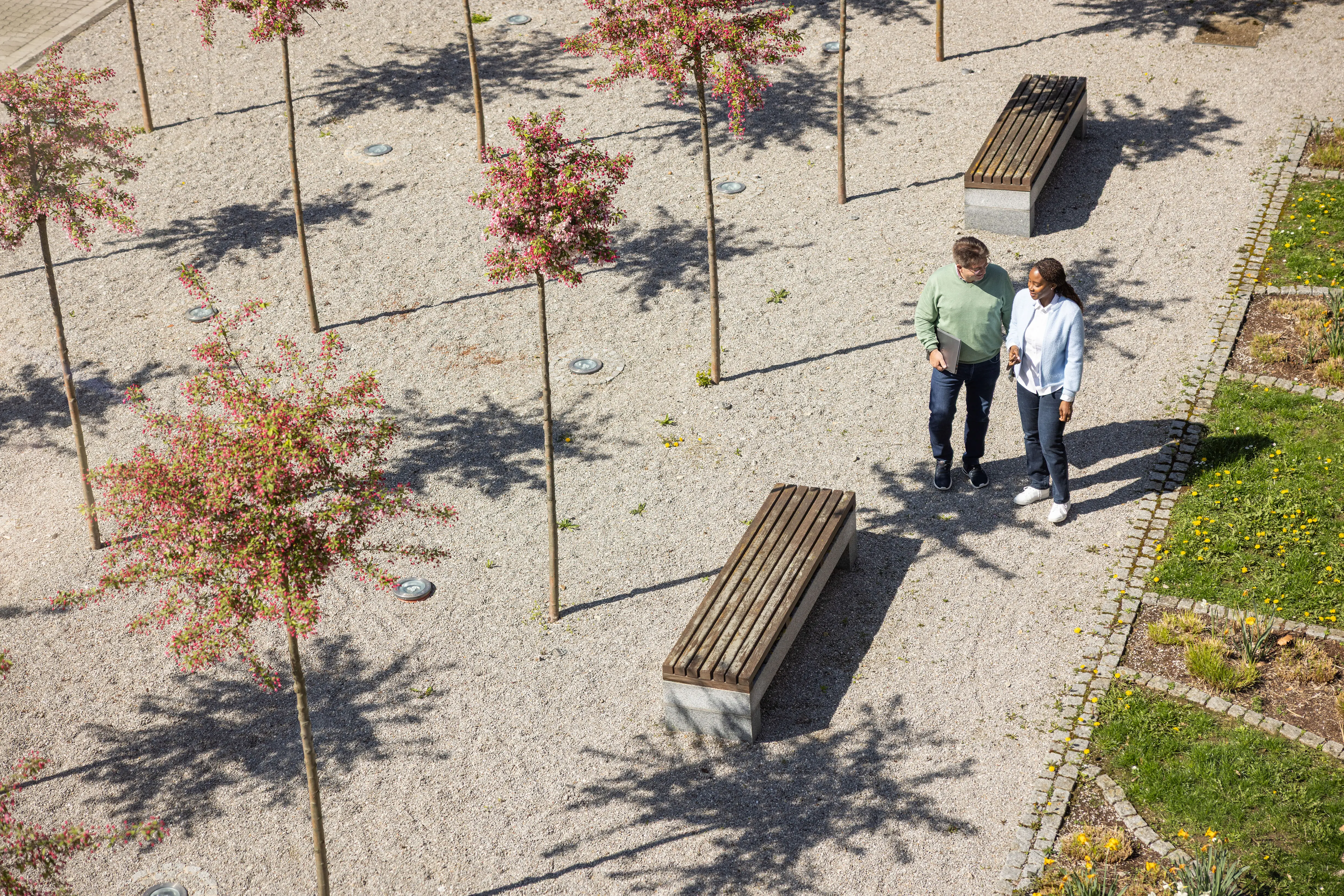 Two people are walking down a staircase, engaged in conversation. One person holds a folder while the other smiles.